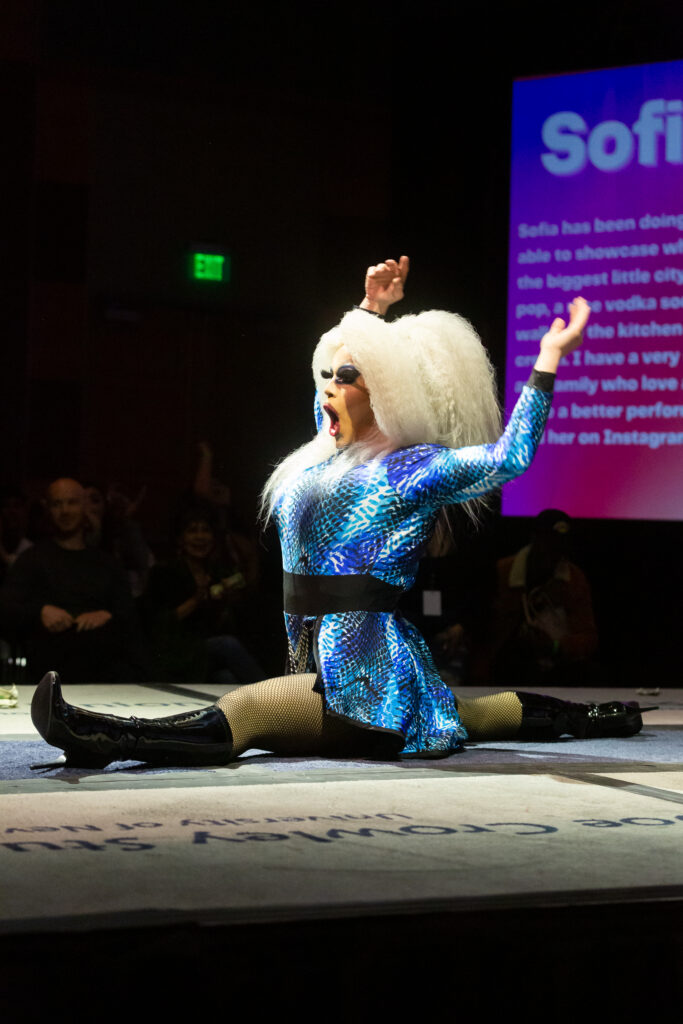 Sofia Evans drops into a split at the end of her performance with her hands up next to her big white wig.