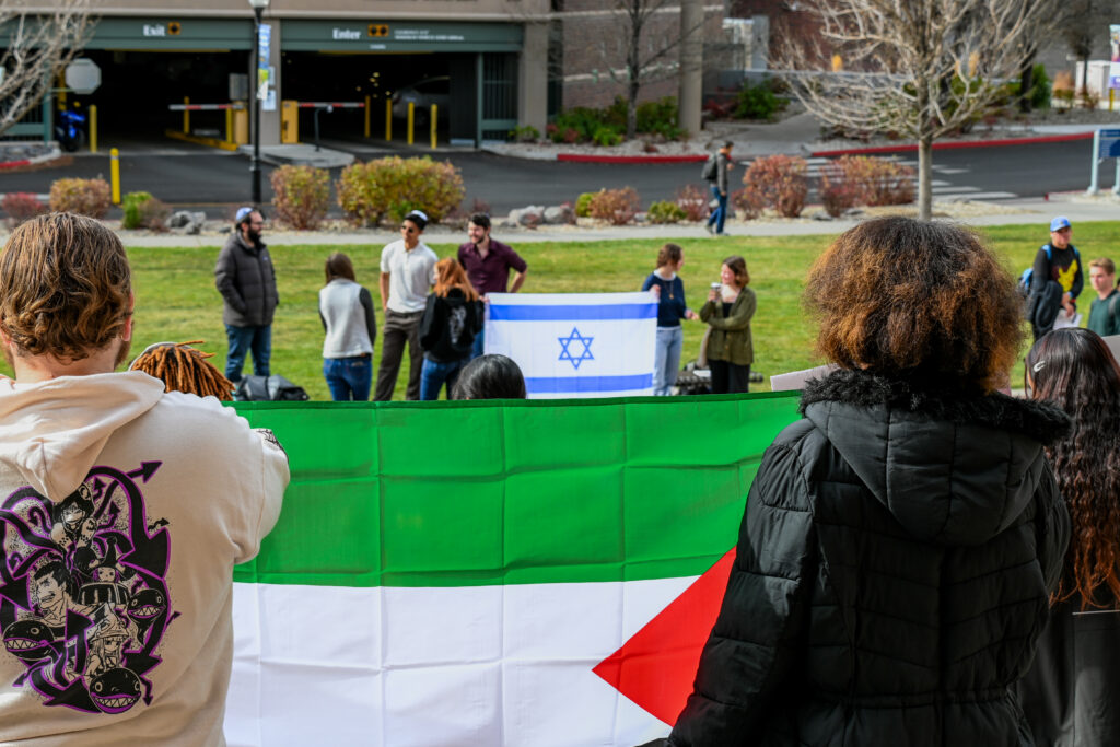 A Palestinian flag in the foreground and the Israeli flag in the background