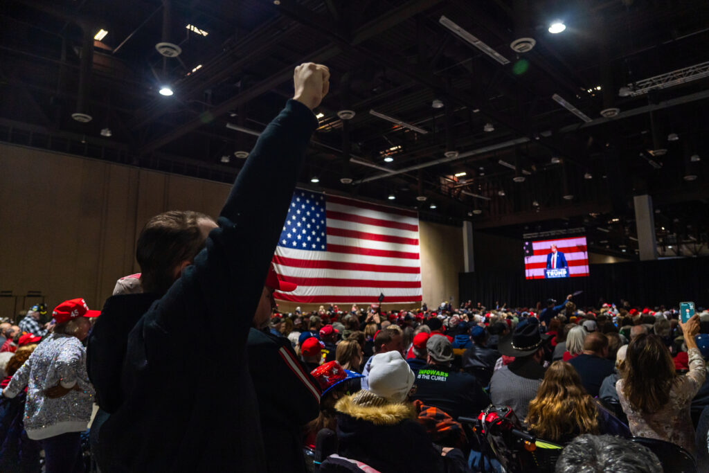 Man holds up fist in front of U.S.A flag at Trump Rally in Reno.