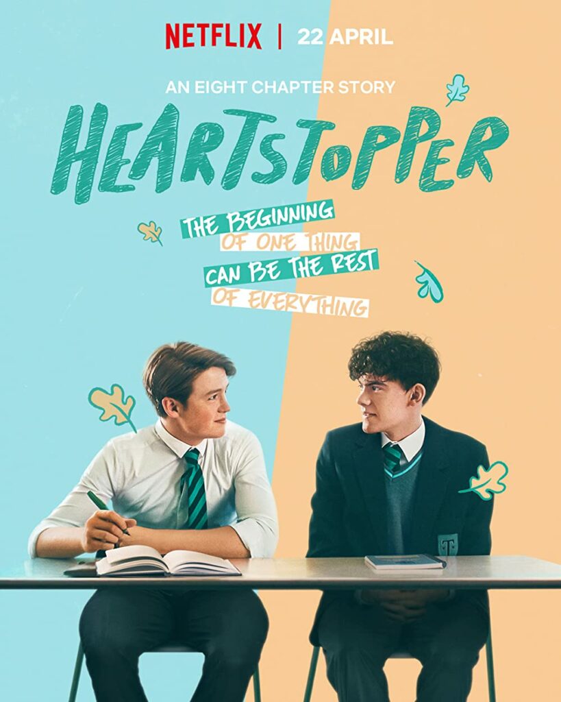 Two boys stare at one another sitting at a desk with a blue and orange background and the title feature "Heartstopper" at the top.