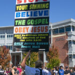Daniel John Lee holds up a sign that says "Stop your sinning. Believe the Gospel and Obey Jesus" in front of students at the Joe Crowley Student Union on UNR campus.