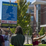 Daniel John Lee holds up a sign that says "Warning to all sinners. Hell awaits. Judgment is coming." in front of students at the E.L Wiegand Fitness Center on UNR campus.