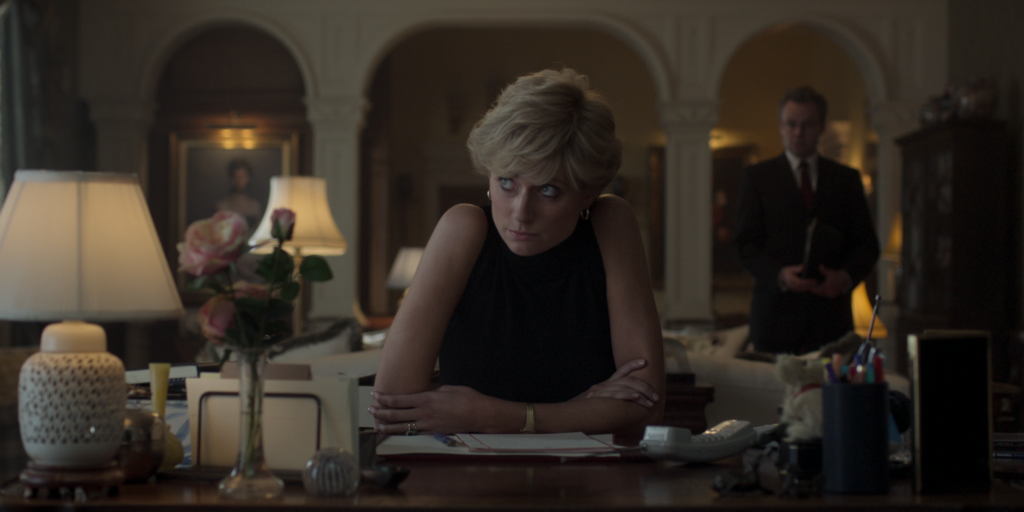 A woman with short blonde hair crosses her arms at a desk. (Still from Netflix's The Crown.)