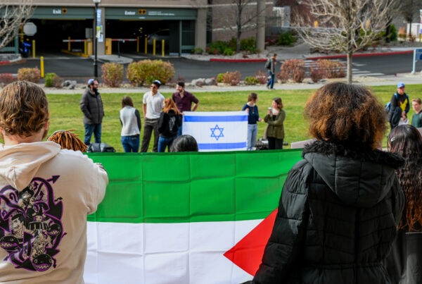 A Palestinian flag in the foreground and the Israeli flag in the background