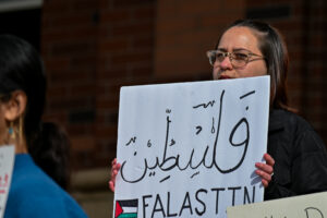 A protestor holds up a sign written in Arabic in support of Palestine