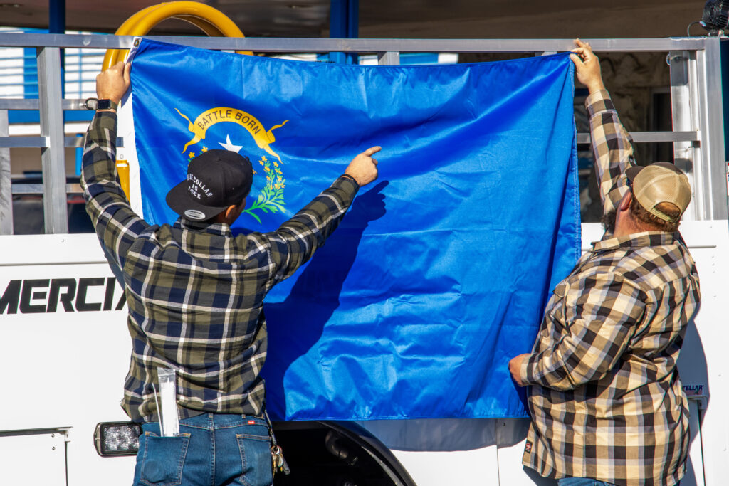 Two men in flannels post up a Nevada flag on their truck.