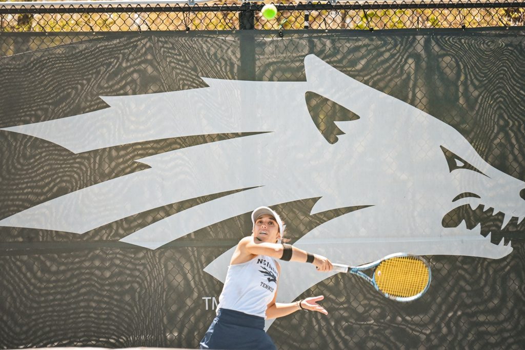 Women's tennis player watches the ball as she winds up to swing.
