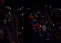 Vaugn Weems looks out into the court and the lights are off and the audience holds their phone lights up.