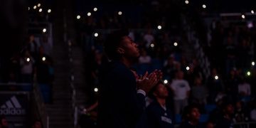 Vaugn Weems looks out into the court and the lights are off and the audience holds their phone lights up.
