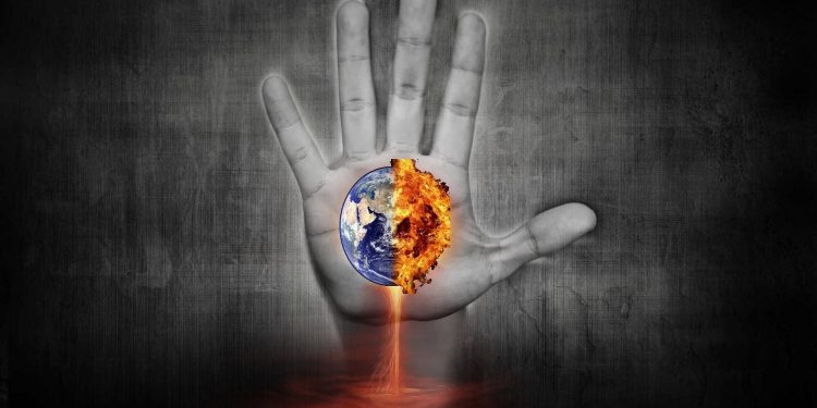 An image of a hand reaching up towards a burning Earth.