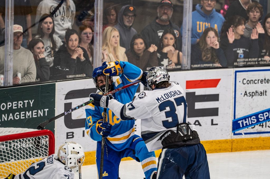 The crowd watches as Nevada hockey defender McLoughlin (#37) pushes a UCLA player off the puck on Oct. 9 at Reno Ice.