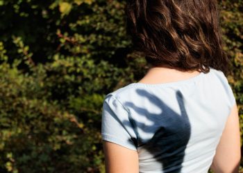 A shadow hand over a girl's shoulder