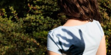 A shadow hand over a girl's shoulder