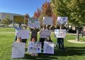 Students and community members holding up their signs at the Joe Crowley Student Union plaza before the protest began on Thursday, Oct. 8.