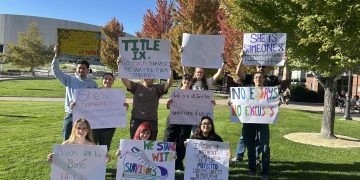 Students and community members holding up their signs at the Joe Crowley Student Union plaza before the protest began on Thursday, Oct. 8.