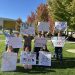 Students and community members holding up their signs at the Joe Crowley Student Union plaza before the protest began on Thursday, Oct. 8.