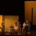 The Outsiders cast conversing on stage during a scene.