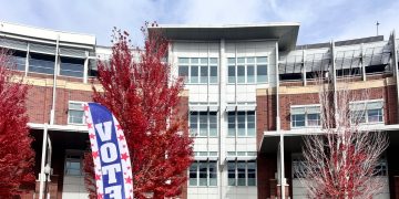 A flag reading “Vote Here” in front of the Joe Crowley Student Union on Oct. 29, 2026.